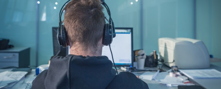 A Journalist sitting at a computer wearing headphones