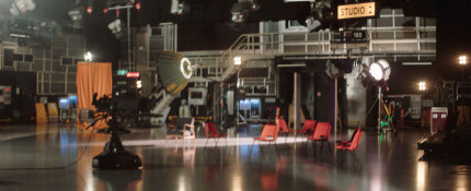 A wide view of an empty TV studio containing equipment such as video cameras