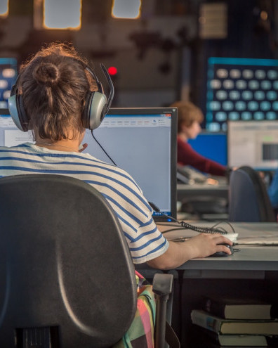 Woman at computer screen with headphones on